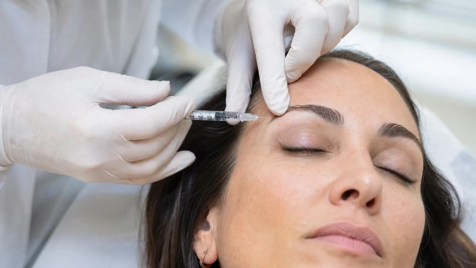 Practitioner administering a Botox injection to smooth forehead lines